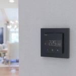 Inteligentný termostat na stene v domácnosti s nastavenou teplotou